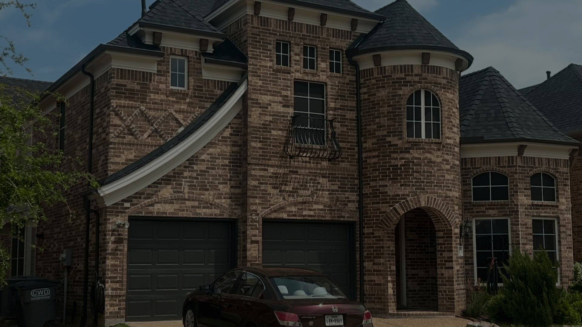 Two-story brick home with a turret and dark shingle roof