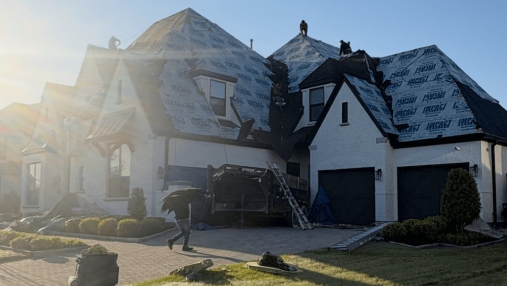 White brick two-story home with a ladder set up for a roof inspection