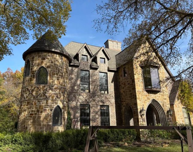 Stone house with steep gables and a turret under a dark shingle roof