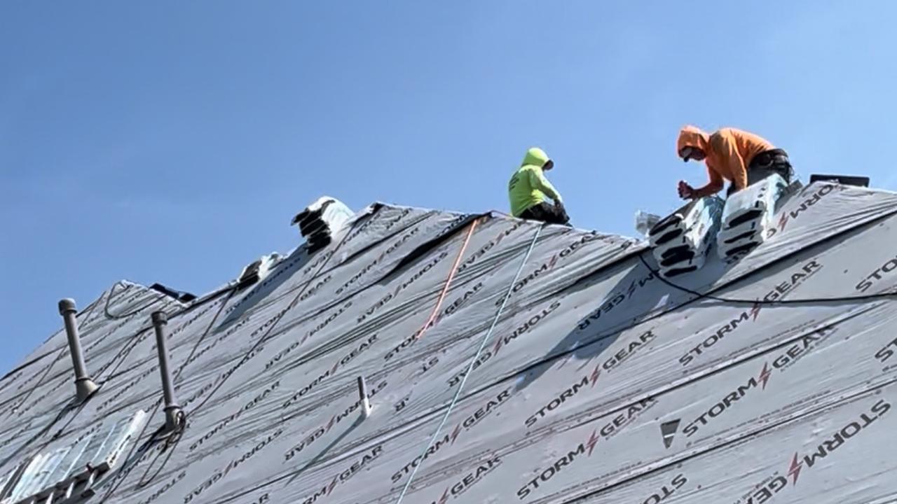 Different Roofing crew installing synthetic underlayment during a roof replacement